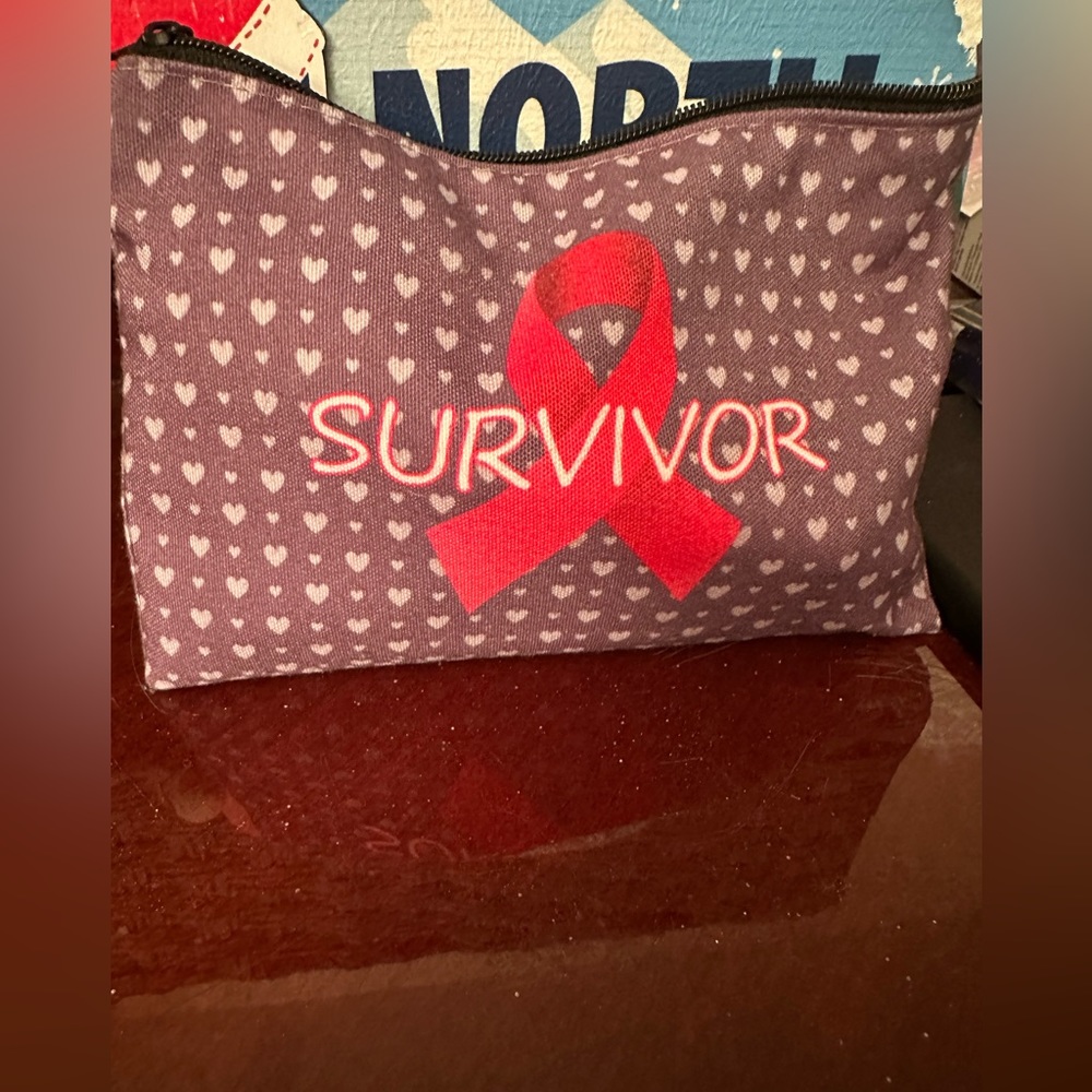 Makeup pouch that says Survivor on it with a pink ribbon symbol.